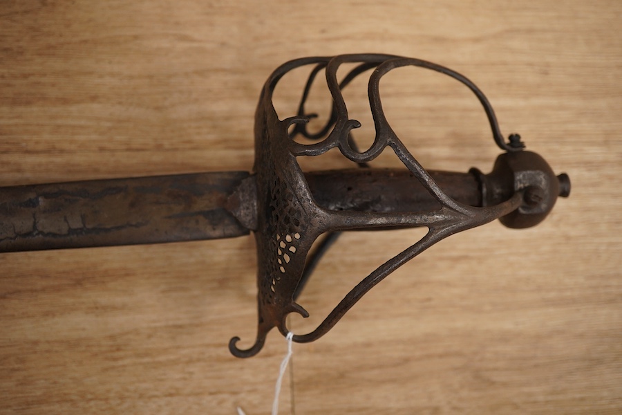 A basket hilted broadsword c.1640, later replacement blade, iron hilt of multi bars with remains of pierced guard, faceted pommel with its original wooden grip, wire covering missing, blade 79cm